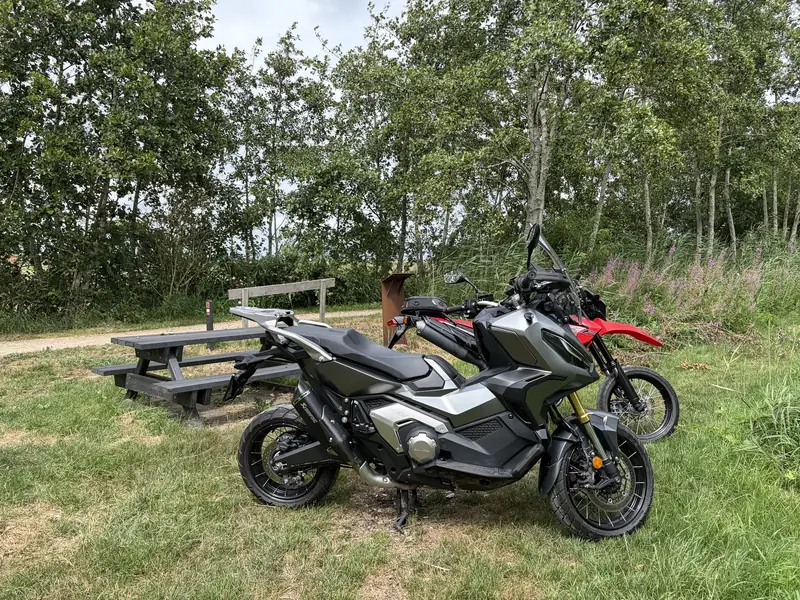 My Honda X-ADV and my dad’s red motorcycle, parked by a picnic table among the trees